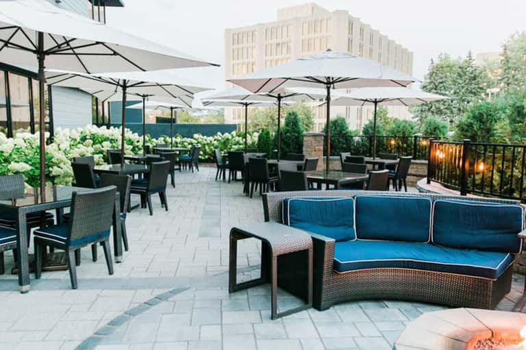 Rooftop terrace with white umbrellas, modern seating, white hydrangeas, and city skyline