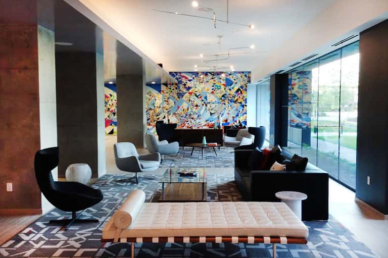 Modern resort lounge with colorful abstract wall art, black furniture, geometric patterns, and floor-to-ceiling windows