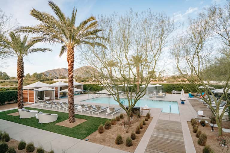 Desert resort pool area with palm trees, cabanas, and mountain backdrop