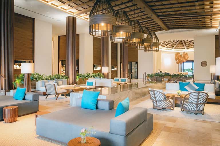 Modern hotel lobby with geometric pendant lights, wood accents, and blue cushioned seating