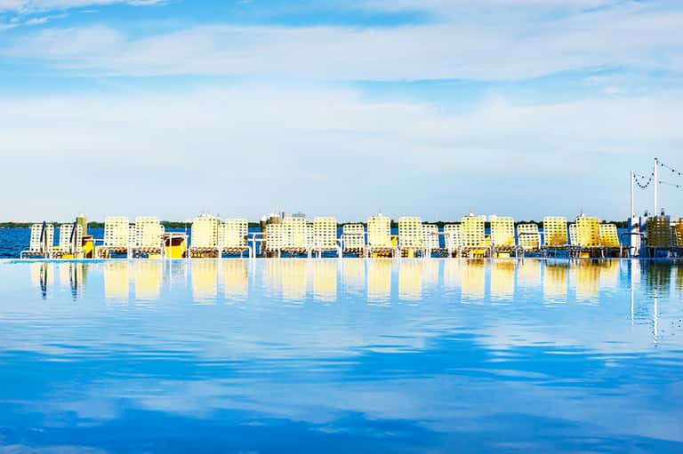 Yellow beachfront buildings reflected in calm blue water