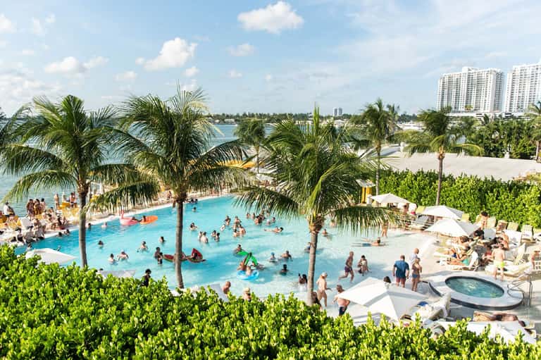 Aerial view of resort pool complex with palm trees and beachfront access