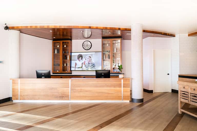 Modern hotel reception desk with wooden finishes, white columns, and contemporary art