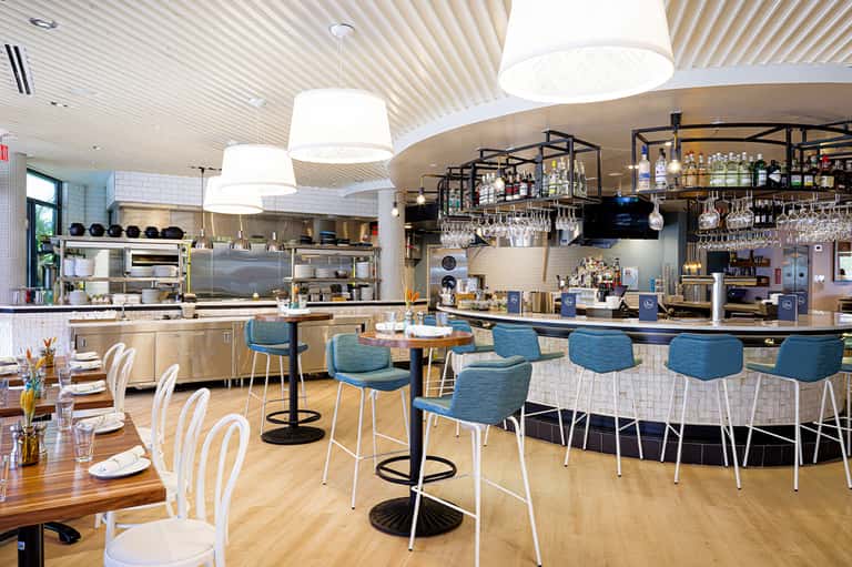 Modern hotel restaurant and bar with open kitchen, curved counter, and contemporary seating