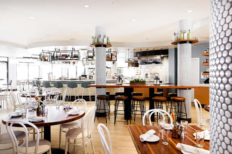 Modern restaurant interior with bar seating, dining tables, and contemporary design elements
