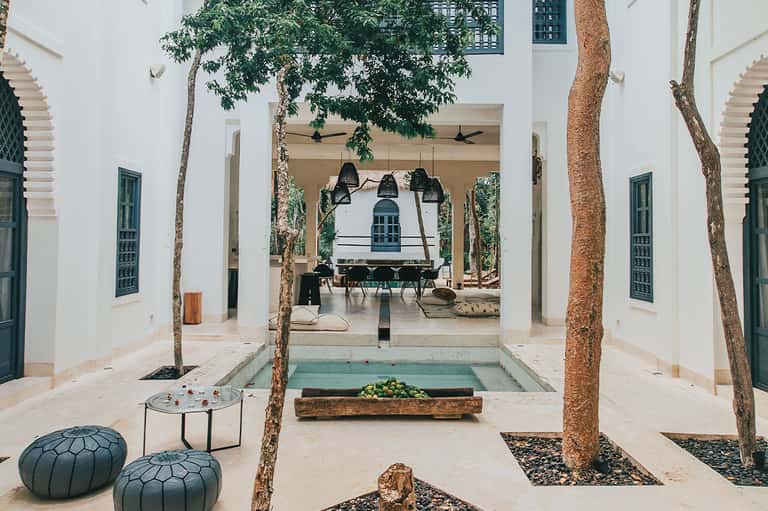Moroccan-style courtyard with white walls, arched colonnade, and central water feature