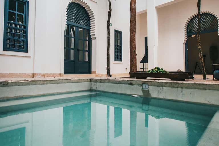 Serene turquoise courtyard pool with white colonial architecture and arched doorway