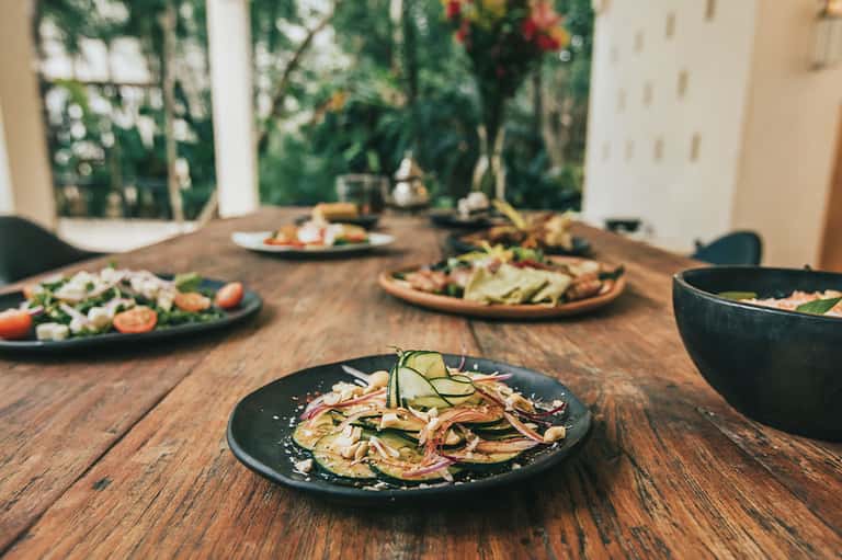 Gourmet salad and vegetable plates on wooden table with garden view background