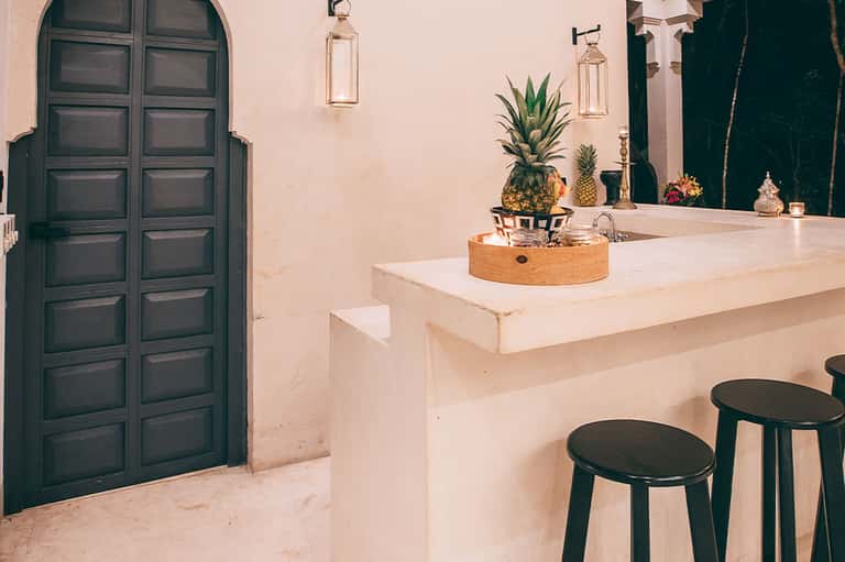 Minimalist spa or wellness area with travertine counter, black doors, and pineapple decor