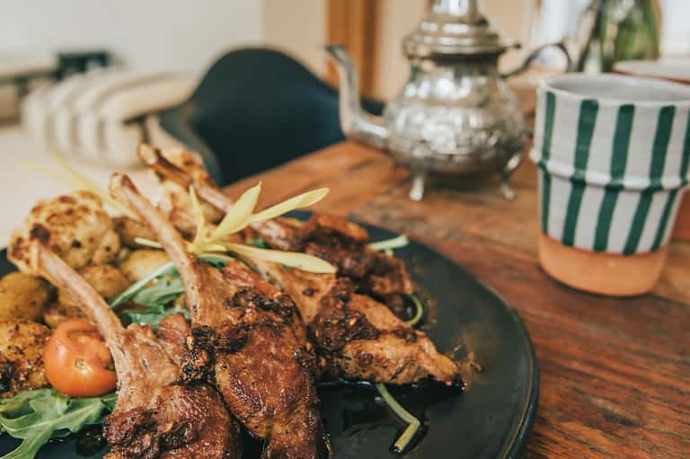 Grilled lamb chops plated on wood serving board with herbs at upscale resort dining