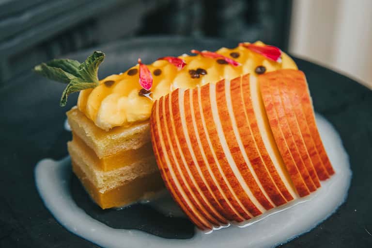 Gourmet plated dessert with cake and thinly sliced apple on elegant dinnerware