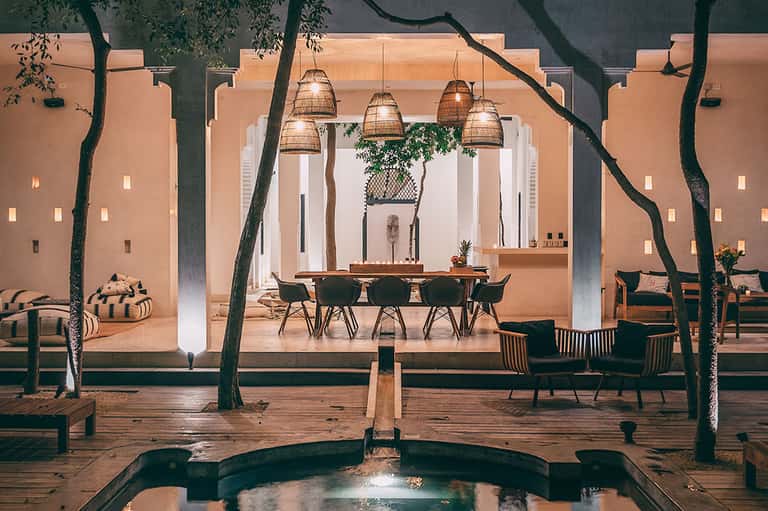 Modern courtyard pavilion with dining table, hanging lights, and water feature