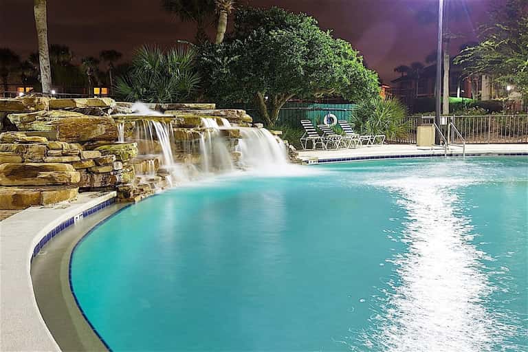 Illuminated resort pool with cascading waterfall at night