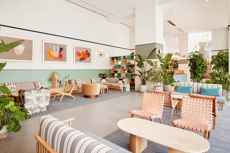 Bright modern lobby with natural wood furniture, plants, and colorful wall art