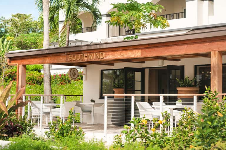 Modern white building exterior with wooden pergola entrance labeled Southwind and tropical landscaping