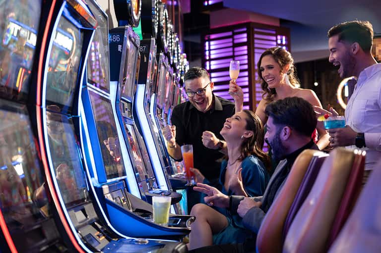 Group enjoying drinks at slot machines in vibrant casino floor