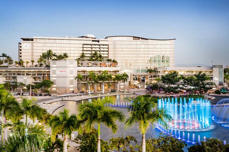 Modern Sheraton hotel with illuminated fountain in foreground and palm-lined promenade