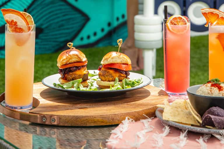 Cocktails and gourmet burgers served poolside with citrus garnishes and appetizers