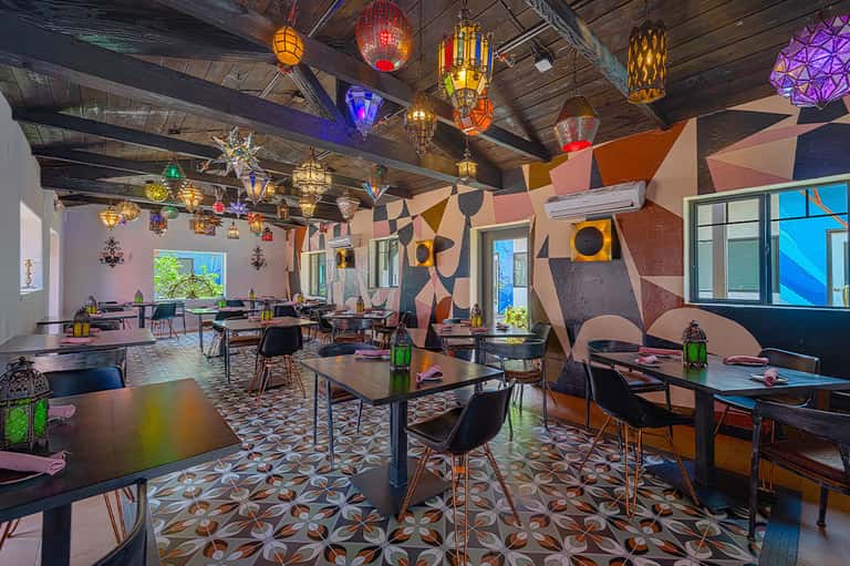 Vibrant restaurant interior with colorful Moroccan lanterns, geometric wall art, and dining tables