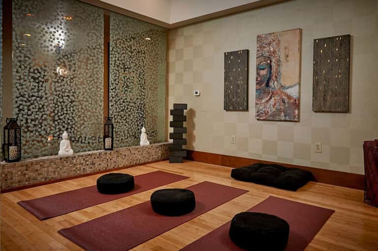 Yoga and meditation studio with wooden floor, mirrored wall, cushions, and modern artwork