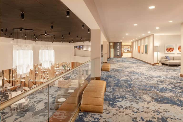 Modern multi-level hotel lobby with pendant lighting, seating areas, and polished flooring