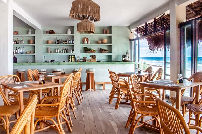 Beachfront restaurant with turquoise walls, wooden furniture, and ocean view