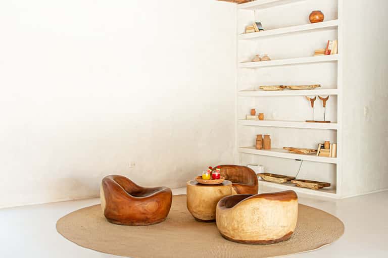 Contemporary lounge with wooden sculptural chairs and shelving displaying decorative objects