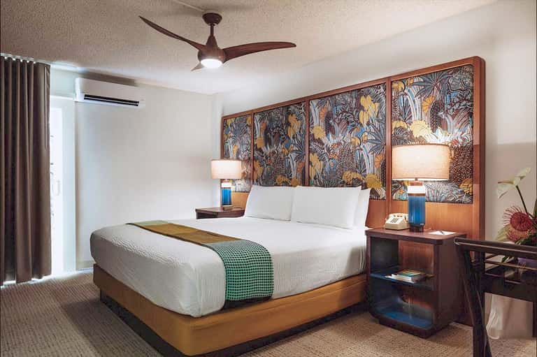 Upscale hotel bedroom with wood headboard, white bedding, and artistic wall panel