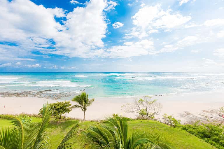 Pristine tropical beach with turquoise waters, palm trees, and white sand under blue sky