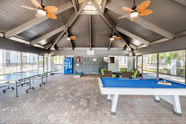Recreation center with pool table, ping-pong table, orange ceiling fans, and window views