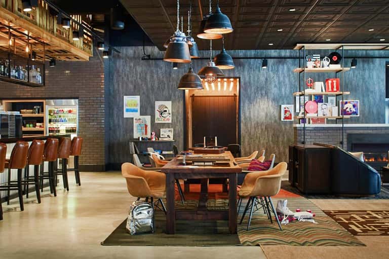 Modern hotel lounge with fireplace, bar seating, and game table