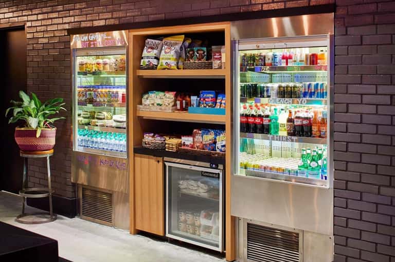 Outdoor beverage station with refrigerated vending machines and shelving stocked with snacks and drinks