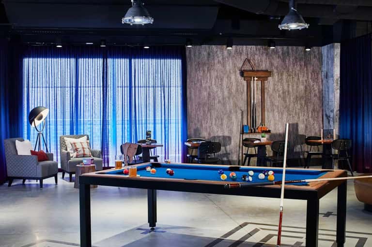 Modern game room with pool table, comfortable seating, floor-to-ceiling windows with ocean view