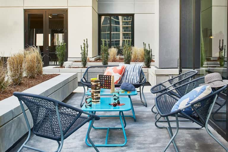 Modern courtyard with blue table, black chairs, and decorative plants and blocks