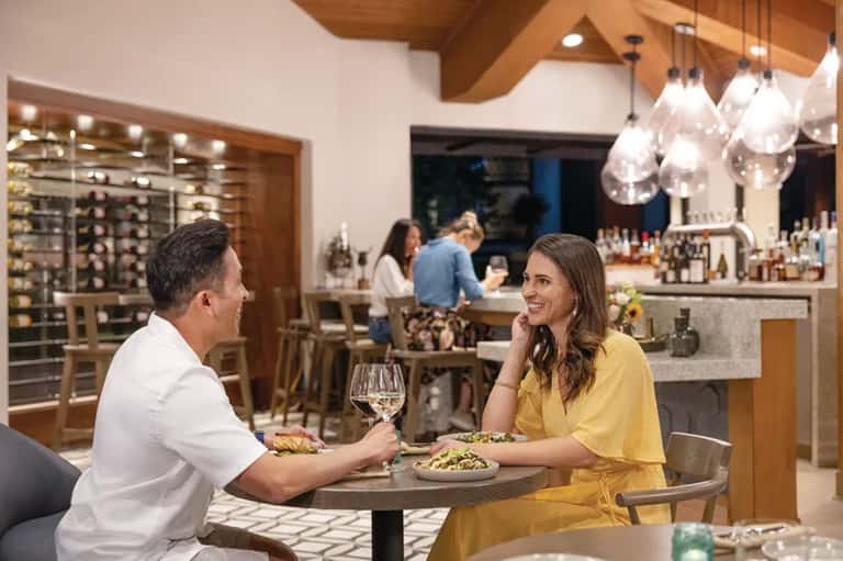 Couple dining at restaurant table with wine glasses and modern bar interior