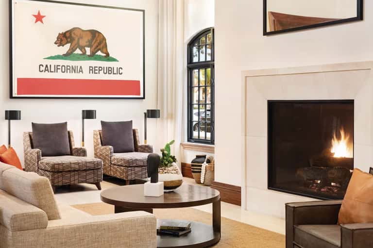 Bright living room with California state flag artwork, fireplace, and neutral modern furnishings