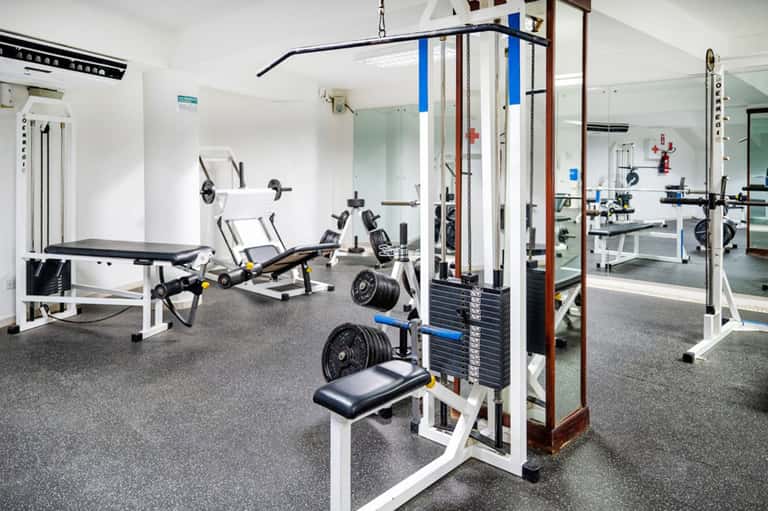 Modern gym facility with weight machines, dumbbells, benches, and mirrored walls