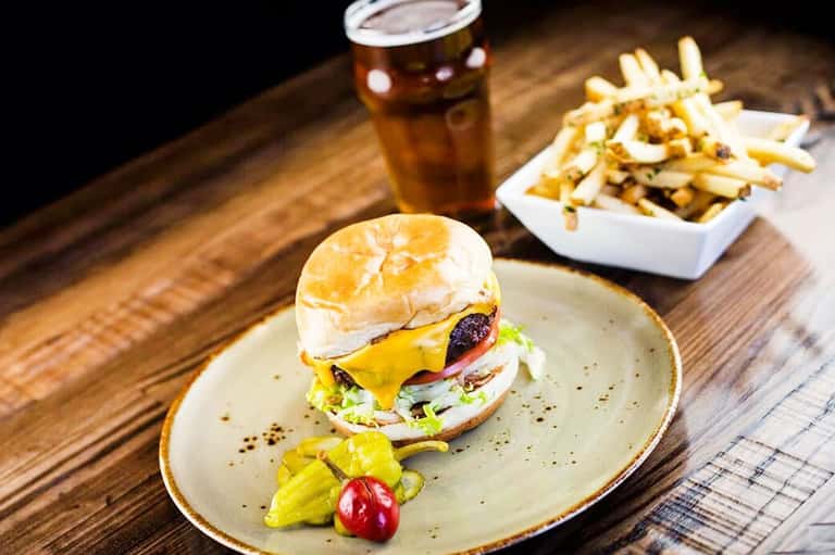 Gourmet burger with melted cheese and fresh vegetables served with fries and cola