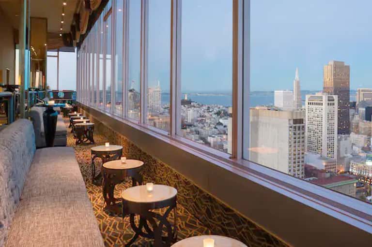 High-rise hotel bar with floor-to-ceiling windows overlooking city skyline