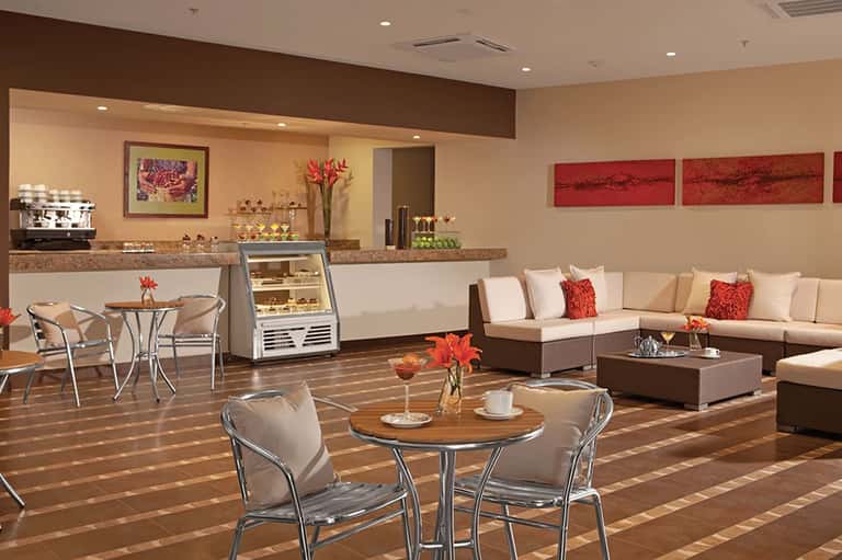 Upscale spa lounge with cream and brown tones, comfortable seating, counter service, and floral décor