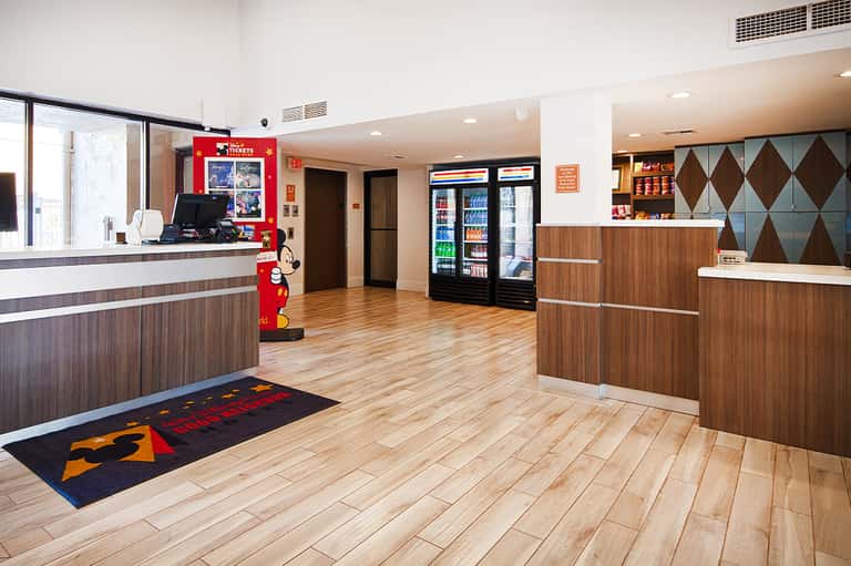 Bright hotel lobby with reception desk, vending machines, and wooden accents