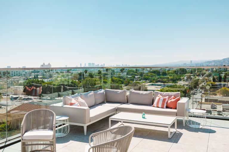 Modern rooftop lounge with sectional seating, glass railings, and expansive city and water views