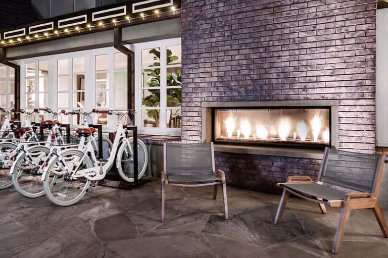 Outdoor patio with fireplace, white bicycles, and modern seating area