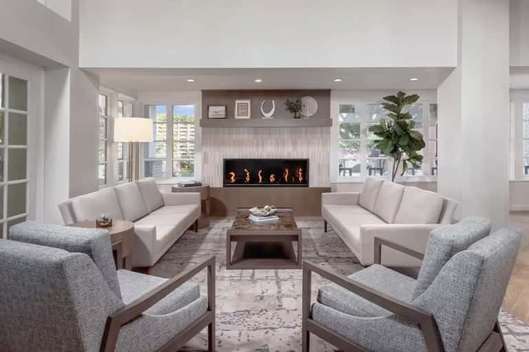 Contemporary living room with fireplace, neutral seating, and floor-to-ceiling windows