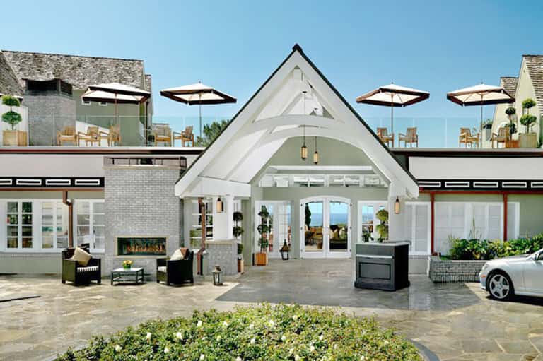 Modern resort entrance with white architectural design, umbrellas, fireplace, and ocean views