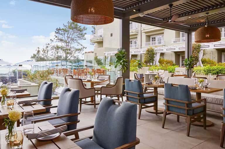 Outdoor dining lounge with comfortable seating, hanging lights, and waterfront views