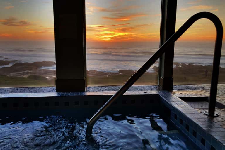 Infinity pool overlooking ocean sunset at dusk with tile details