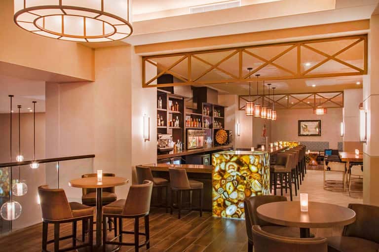 Modern bar and lounge with warm lighting, wooden fixtures, decorative tiles, and seating areas