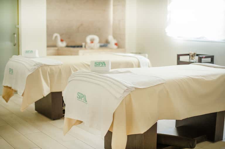 Spa treatment room with massage beds covered in white linens and cream towels
