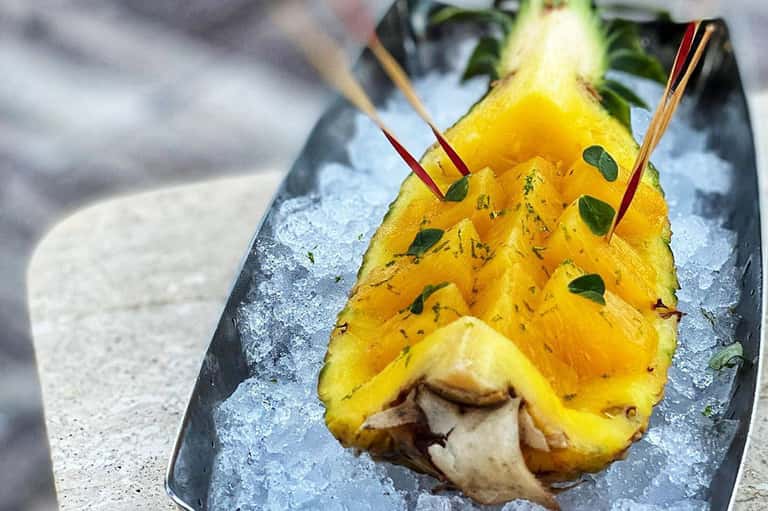 Artfully plated tropical cocktail with fresh pineapple and mint garnish on ice